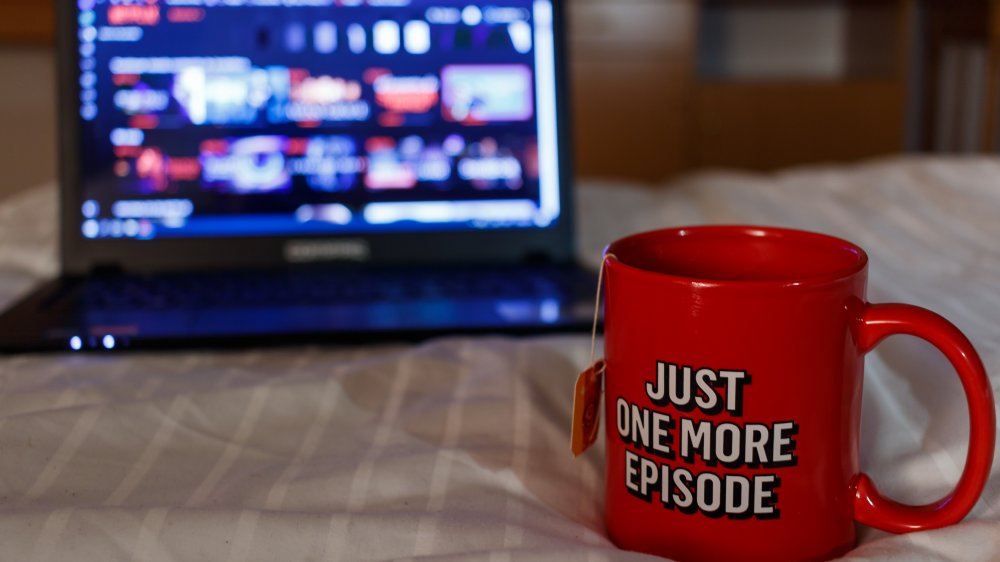 Netflix on laptop, tea in a mug that says "just one more episode"