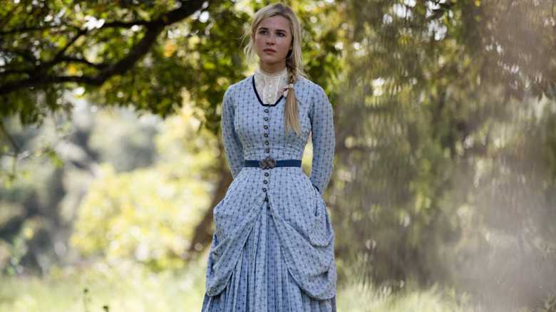 Elsa Dutton in blue dress standing under trees