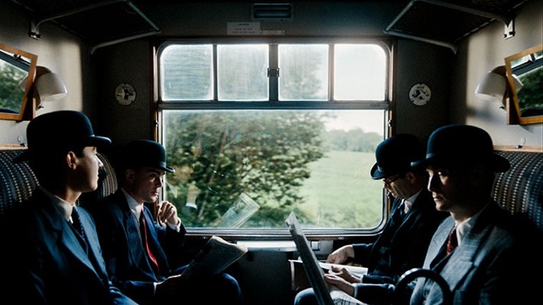 Four men in suits ride in train car
