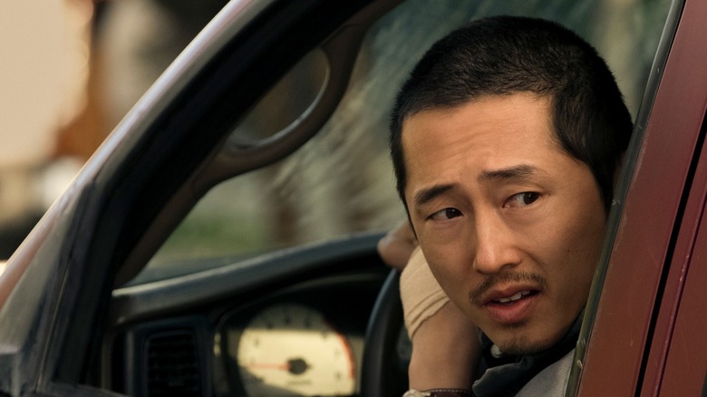 Steven Yeun looking behind his truck