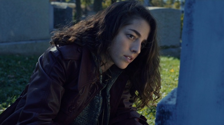 Holly crouching at her mother's grave