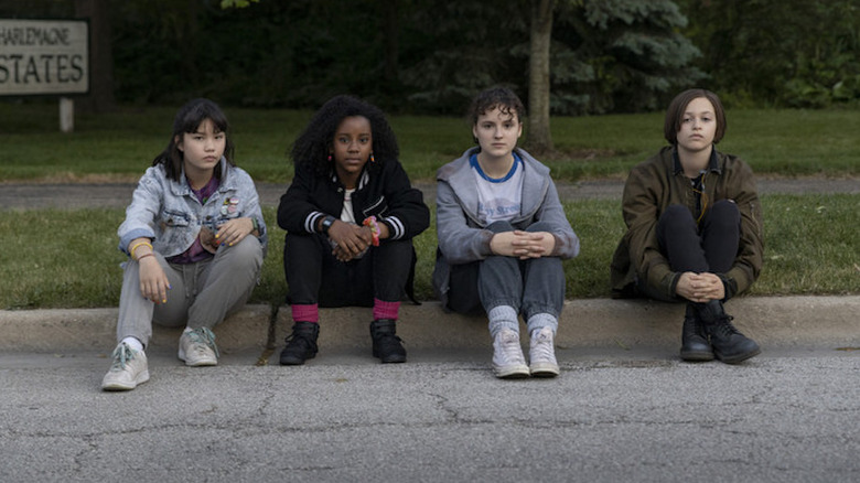 The Paper Girls sitting on curb