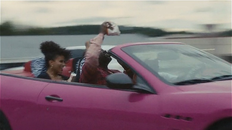 People riding in pink convertible