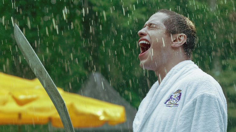 Pete Davidson yelling in the rain with a machette