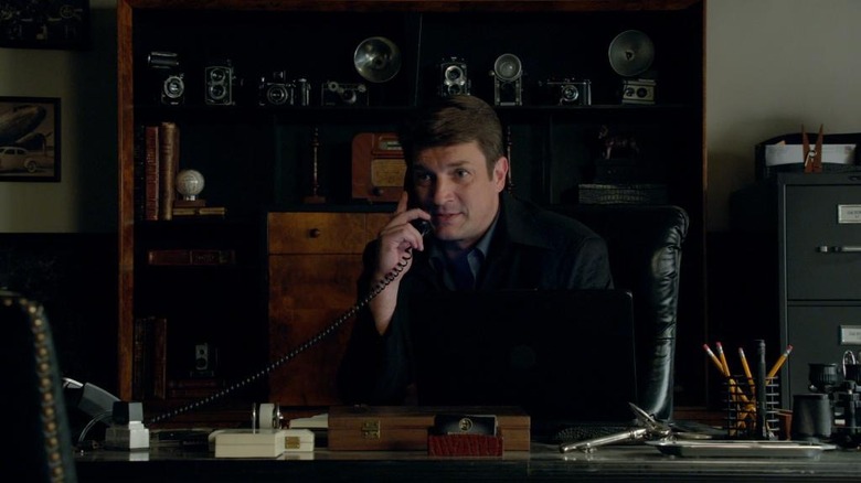 Castle sits in office talking on the phone