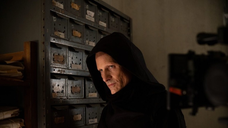 Saul Tenser looks over shoulder in front of file cabinet