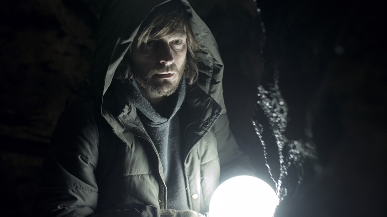 The Stranger holding lantern in cave