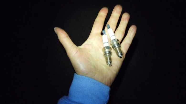 A hand holding spark plugs