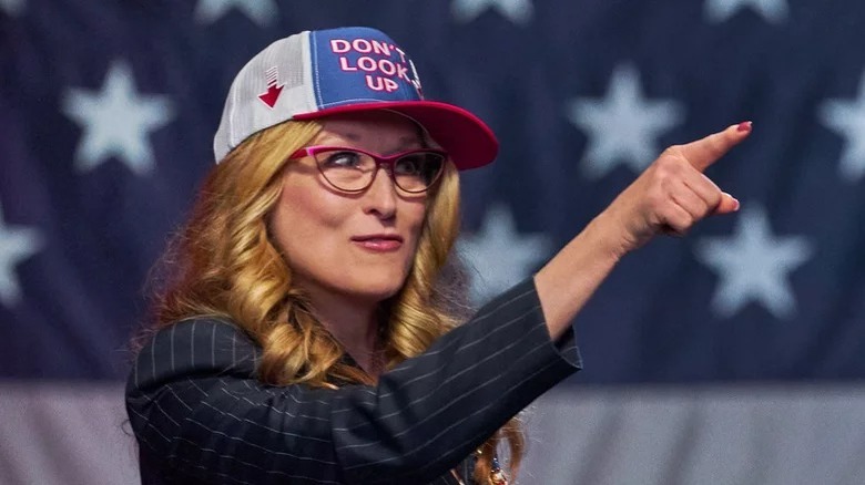 President Janie Orlean points while wearing a "Don't Look Up" hat