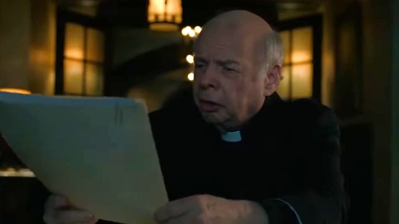 Father Ignatius looking at folder in his hands 