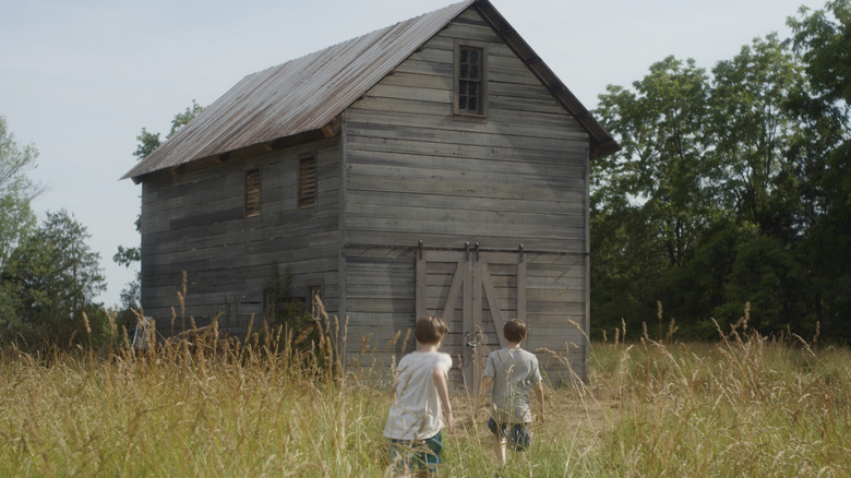 Twin boys run towards barn