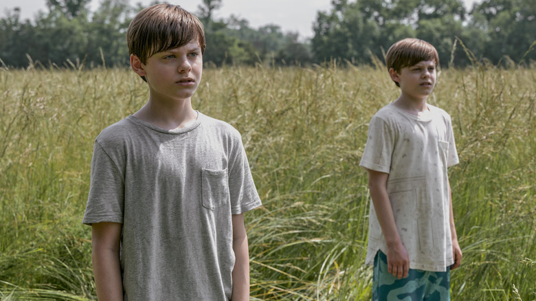 Two boys stand in field