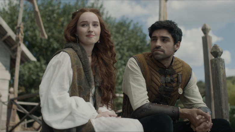 Rosaline and Dario sit together on a dock watching the horizon