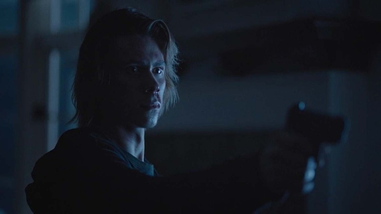 Alec holding gun in the dark