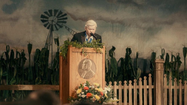 Jake giving a speech against a painted backdrop of a windmill in "I'm Thinking of Ending Things"