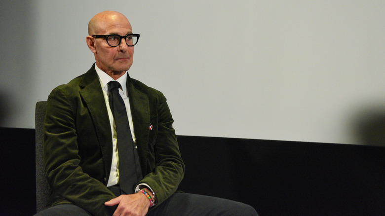 Stanley Tucci sits relaxed on a stage