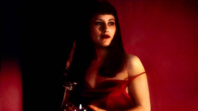 Renee stands against a red wall in a red dress in Lost Highway (1997)