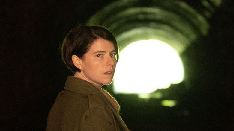 Jessie Buckley looking scared in a tunnel 