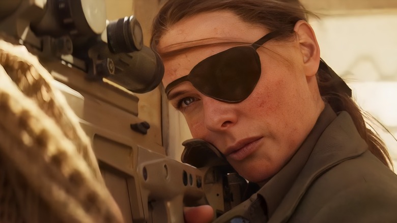 Ilsa aims a sniper rifle