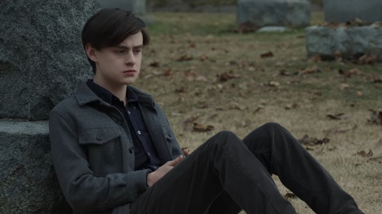 Jaeden Martell sitting against a gravestone