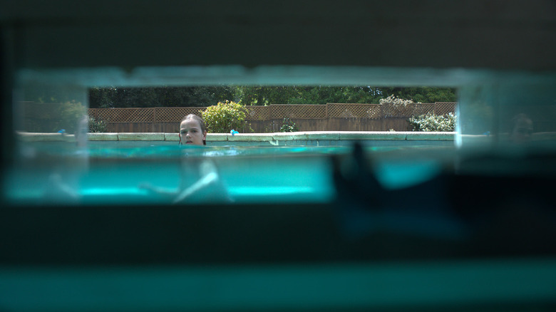 Elliot staring through pool drain