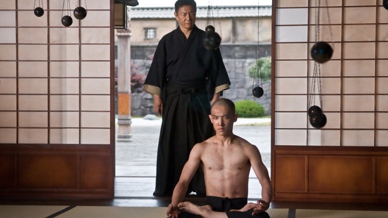 Lord Ozunu standing behind teenage Raizo