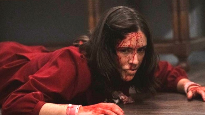 Leena lays on the floor, looking determined with blood on her face