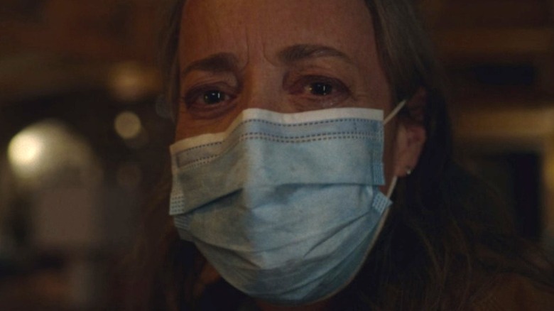 Pamela, tears in her eyes and wearing a face mask