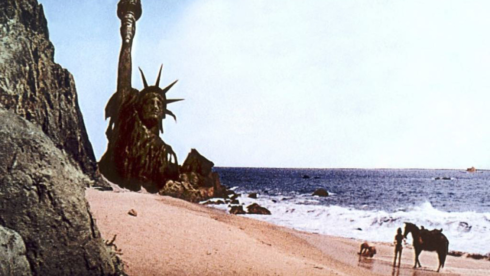 Man kneeling in front of Statue of destructed Statute of Liberty