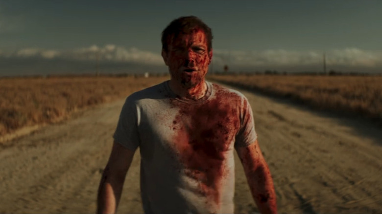 Adam covered in blood standing in the road