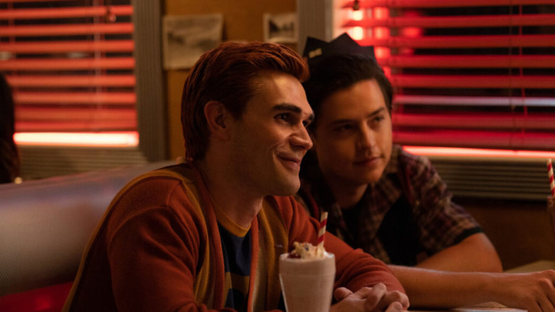 Arche and Jughead smiling over a milkshake