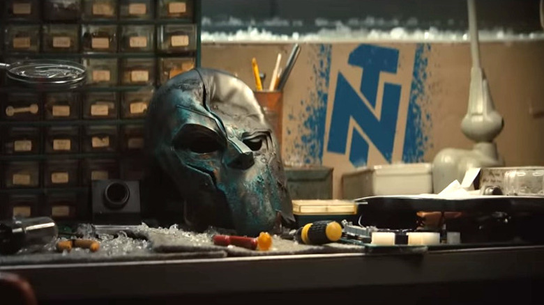 A mask sits damaged on a workbench