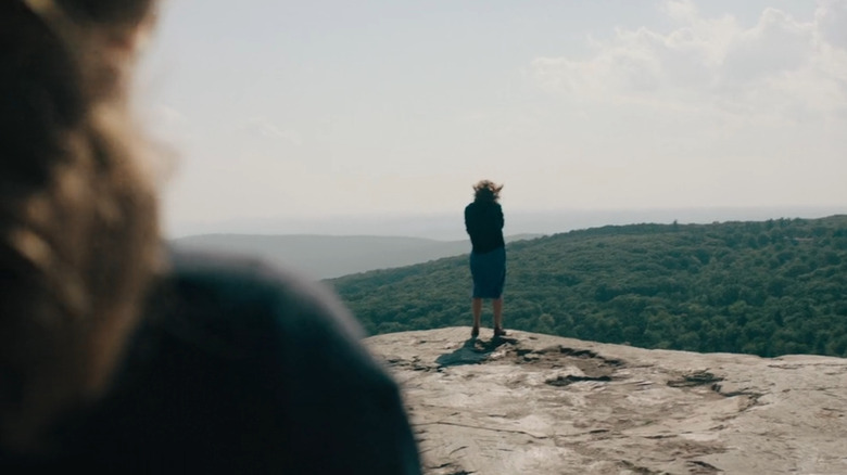 Rose stands on the edge of a cliff