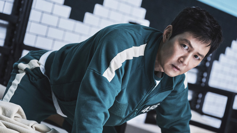 Gi-hun on a bed wearing his green tracksuit