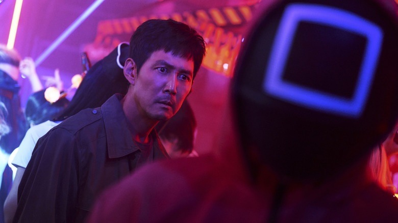 Gi-hun looks at a pink soldier with wide eyes