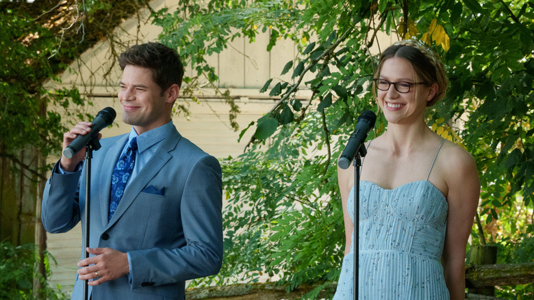 Kara and Winn smiling with mics