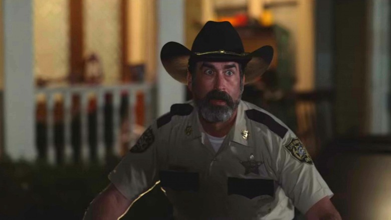 Sully crouches in panic wearing a sheriff uniform