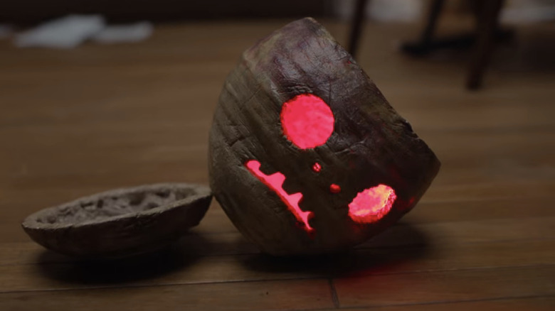 A haunted gourd lies on the floor with red light inside