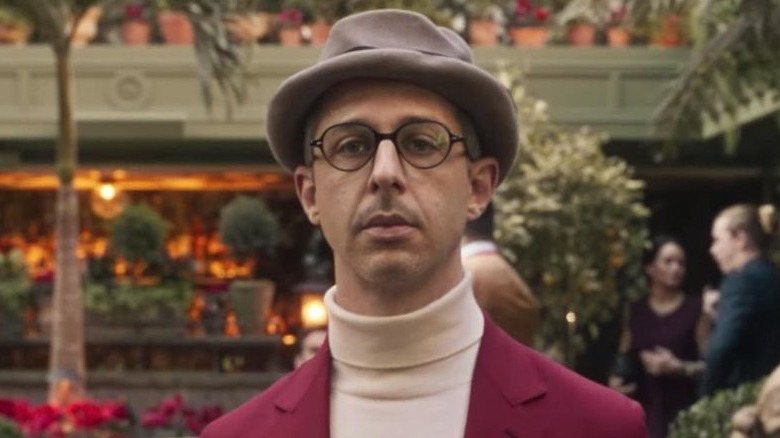 Jeremy Strong wearing white turtleneck, glasses, hat