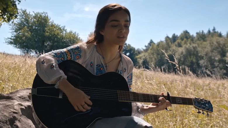 Lucy Gray Baird strumming a guitar