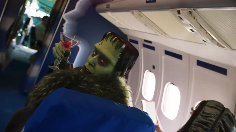 Herman sits on an airplane with a cocktail