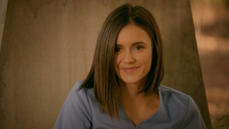 Elena smiles graveside in scrubs