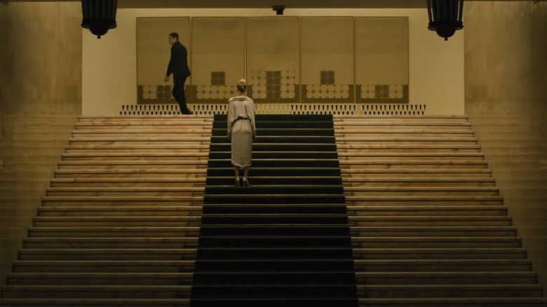 Julia standing on stairs as man passes by