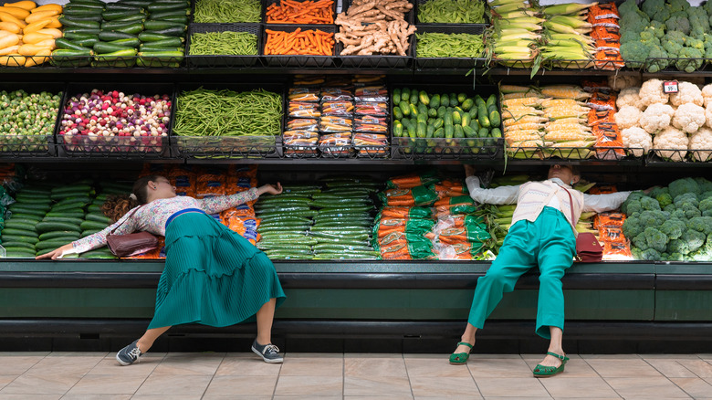 Women lying on supermarket produce