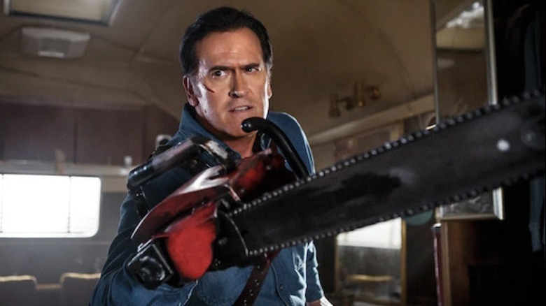 Bruce Campbell as Ash stands with a chainsaw over his right arm