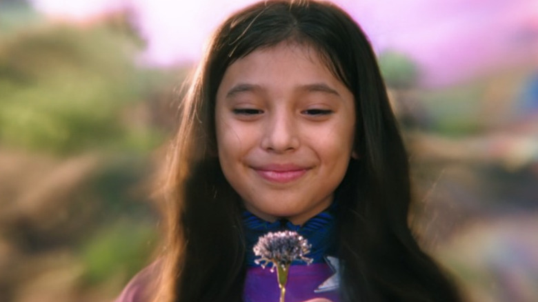 Young America Chavez smiling at flower