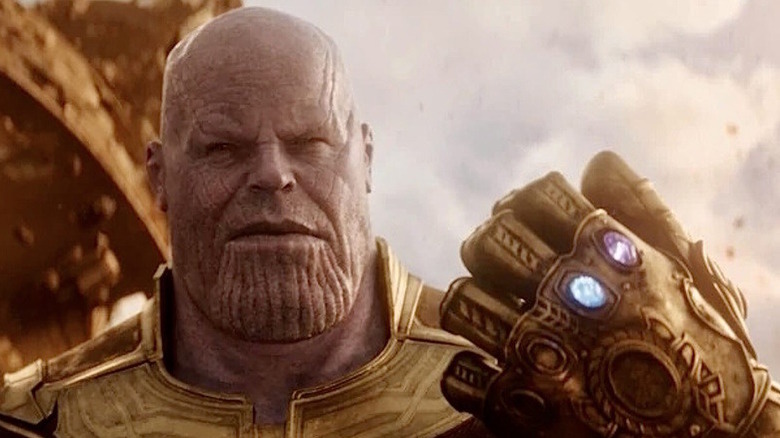 Thanos holds up the Infinity Gauntlet with two stones visible