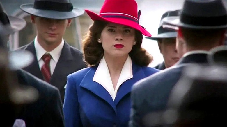 Agent Peggy Carter wearing red hat among crowd of suited men