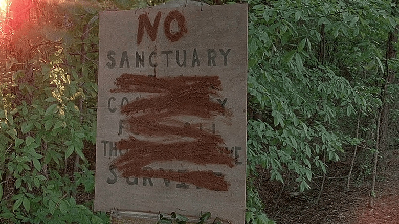 Graffitied sign reads 'No Sanctuary'