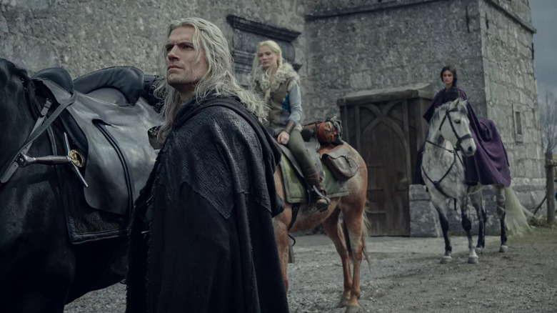 Geralt walks through town with Ciri and Yennefer on horses